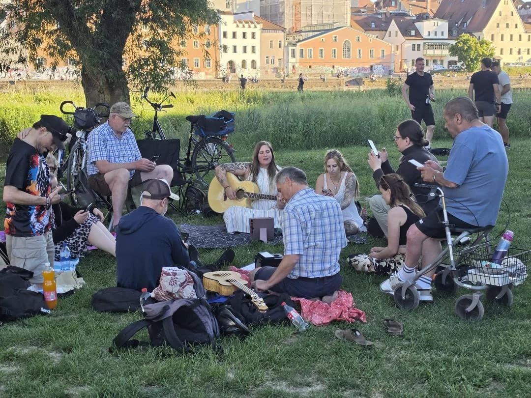 Menschen sitzen auf der Jahninsel und singen gemeinsam.