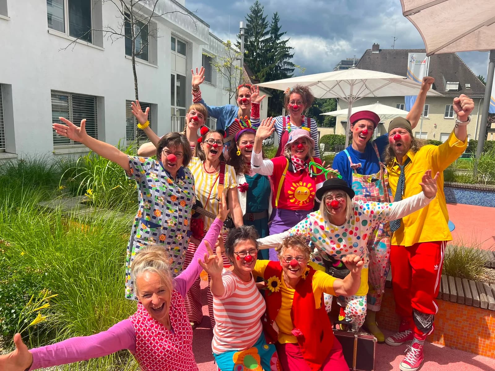 Klinikclowns stehen in einer Ausbildungsgruppe und lachen in die Kamera.