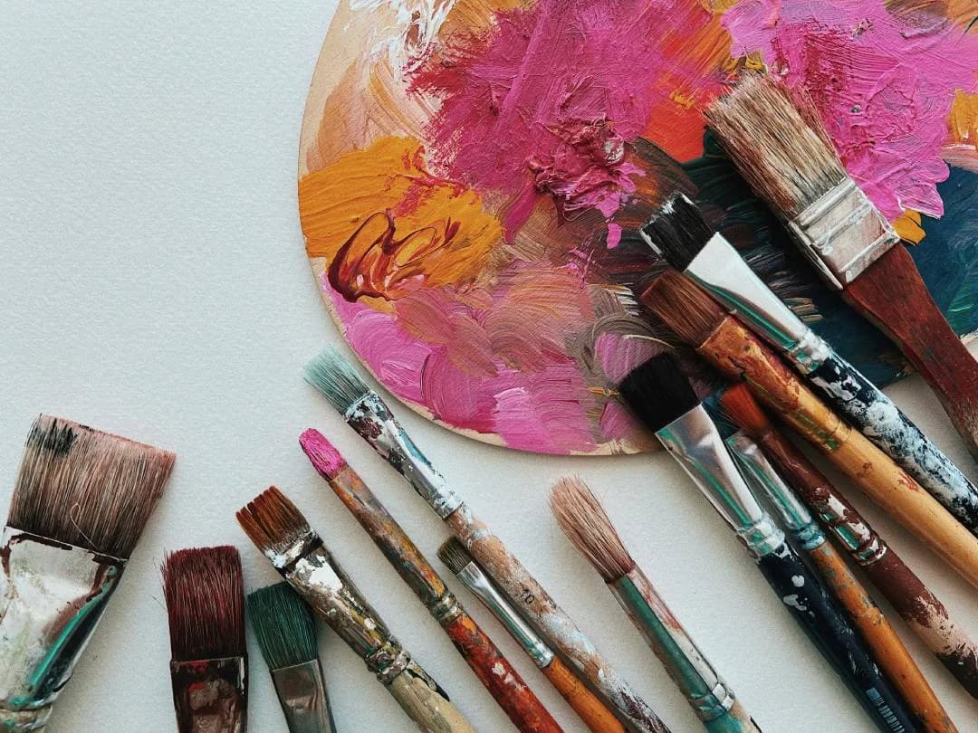 Auf einem Basteltisch liegen Pinsel und Farben.