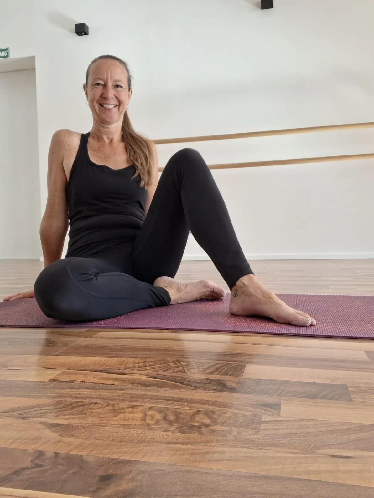 Die Yogalehrerin Sonja sitzt auf einer Yogamatte.