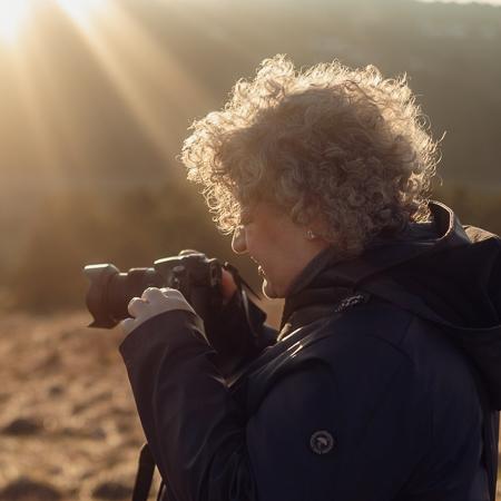 Eine Frau fotografiert bei Sonnenaufgang in der Natur.