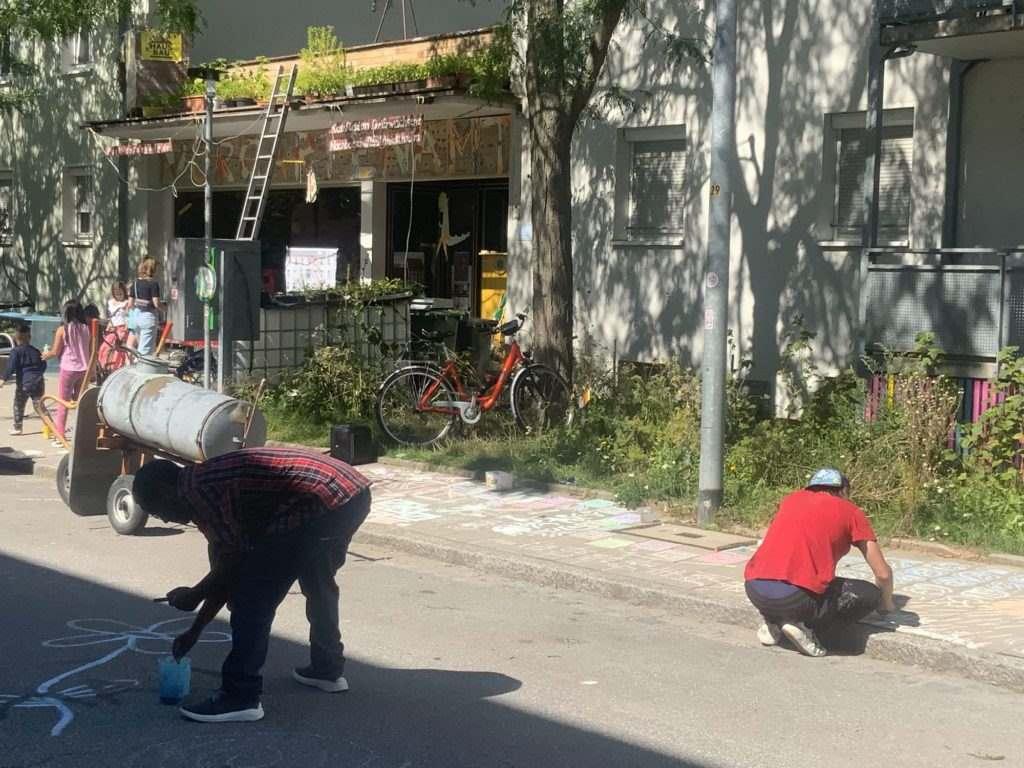 Menschen gestalten und bemalen die Straße vor dem Kaufladen für Erwachsene