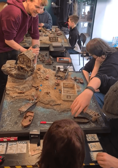 Junge Menschen sitzen an einem Tisch zusammen und bauen an einer Spielelandschaft.