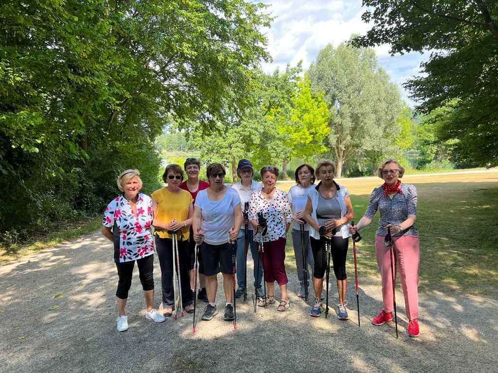Frauen mit Walkingstöcken stehen auf einem Waldweg bei einer Walkingtour.