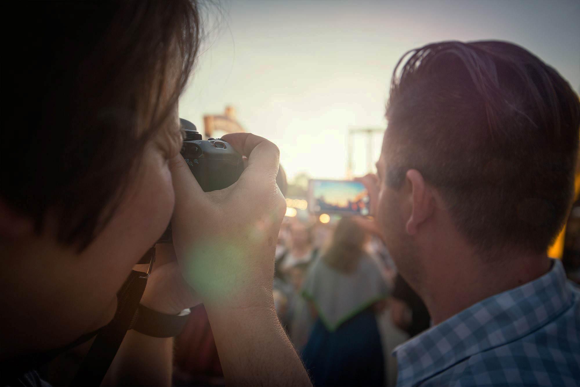 Zwei Menschen mit Fotoapparat fotografieren auf einem Fest.
