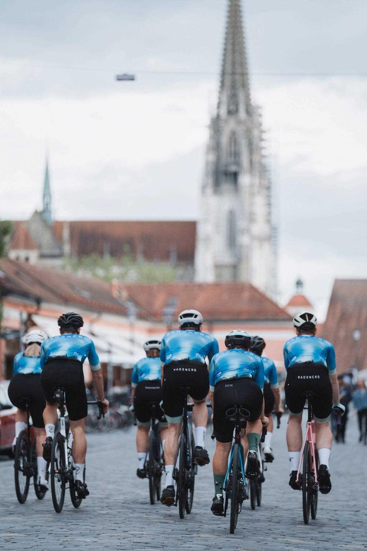 Eine Gruppe von Radfahrern radelt über die Steinerne Brücke vor dem Dom.