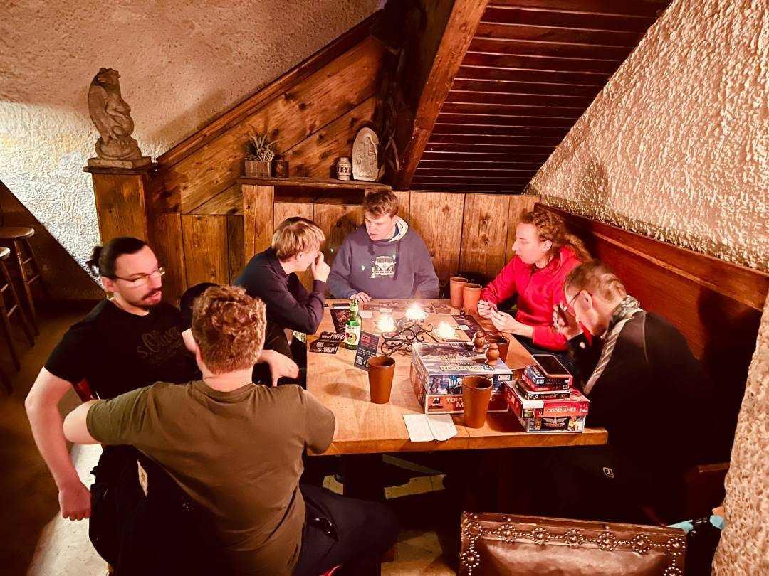 Eine Gruppe Menschen sitzt gemütlich zusammen bei einem Brettspiel.