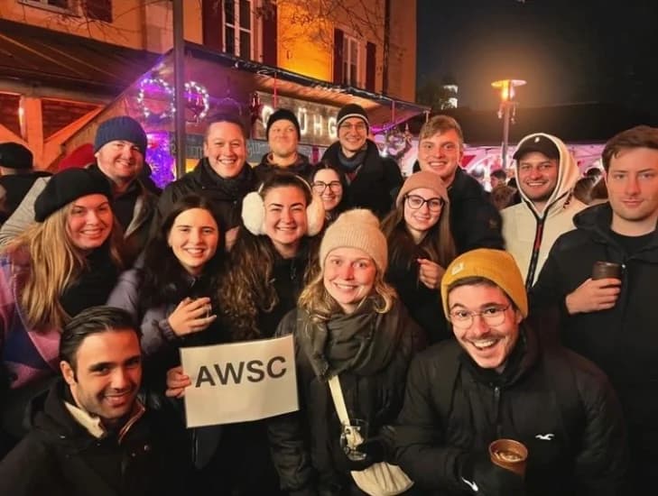 Eine große Gruppe junger Menschen feiert abends in der Stadt.
