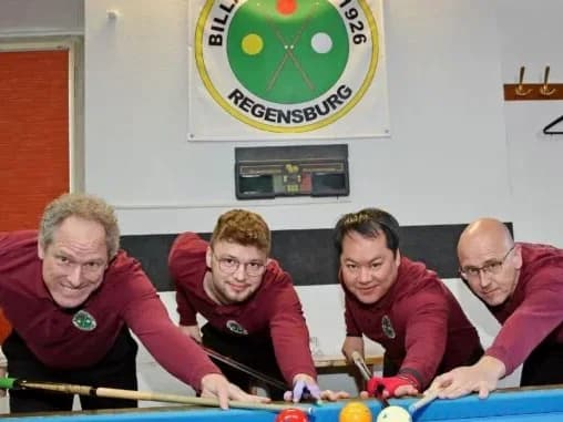 Vier Billiardspieler stehen am Billiardtisch.