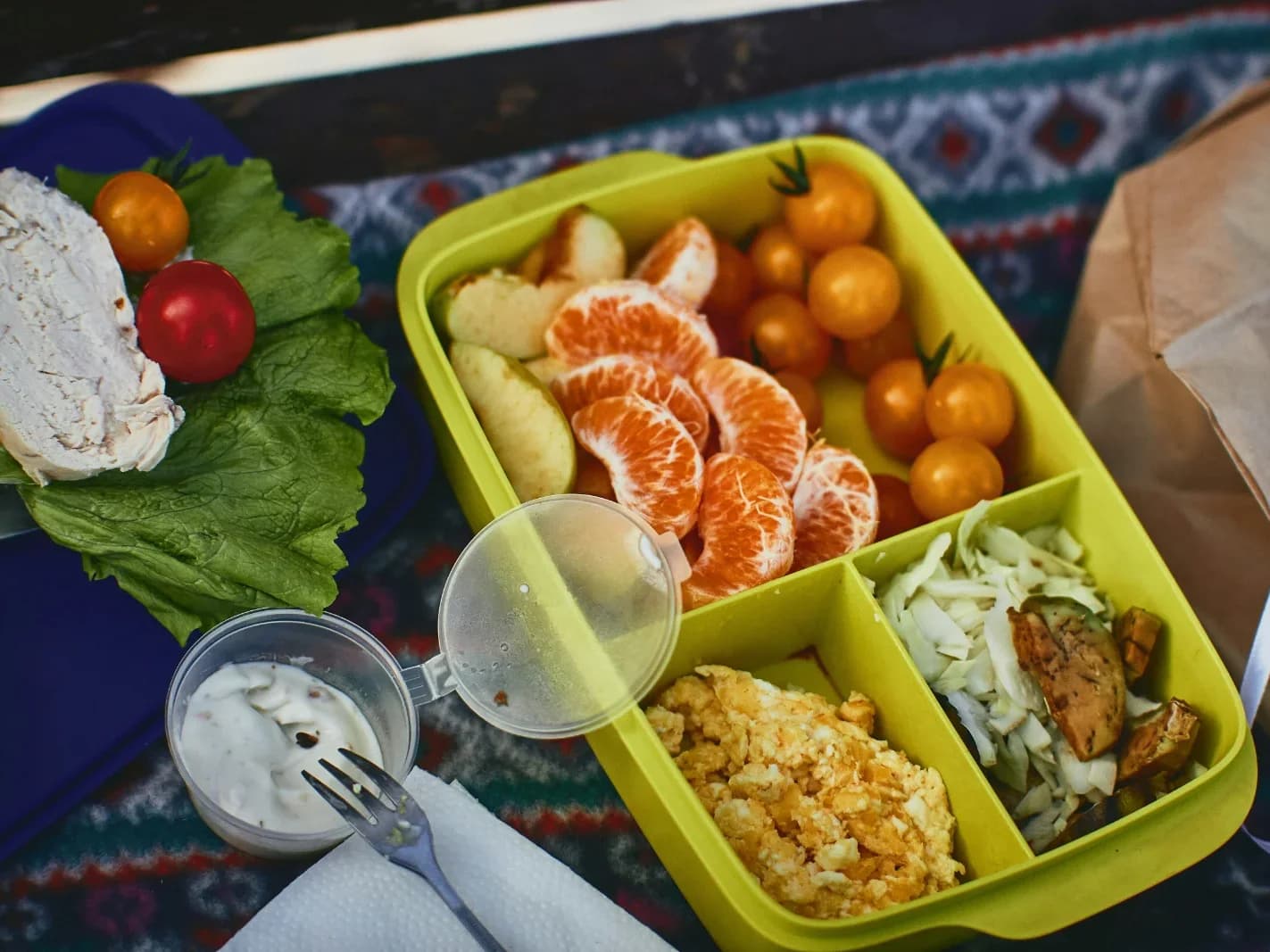 Vier Menschen essen gemeinsam Burger, Pommes und Gemüse an einem runden Tisch.
