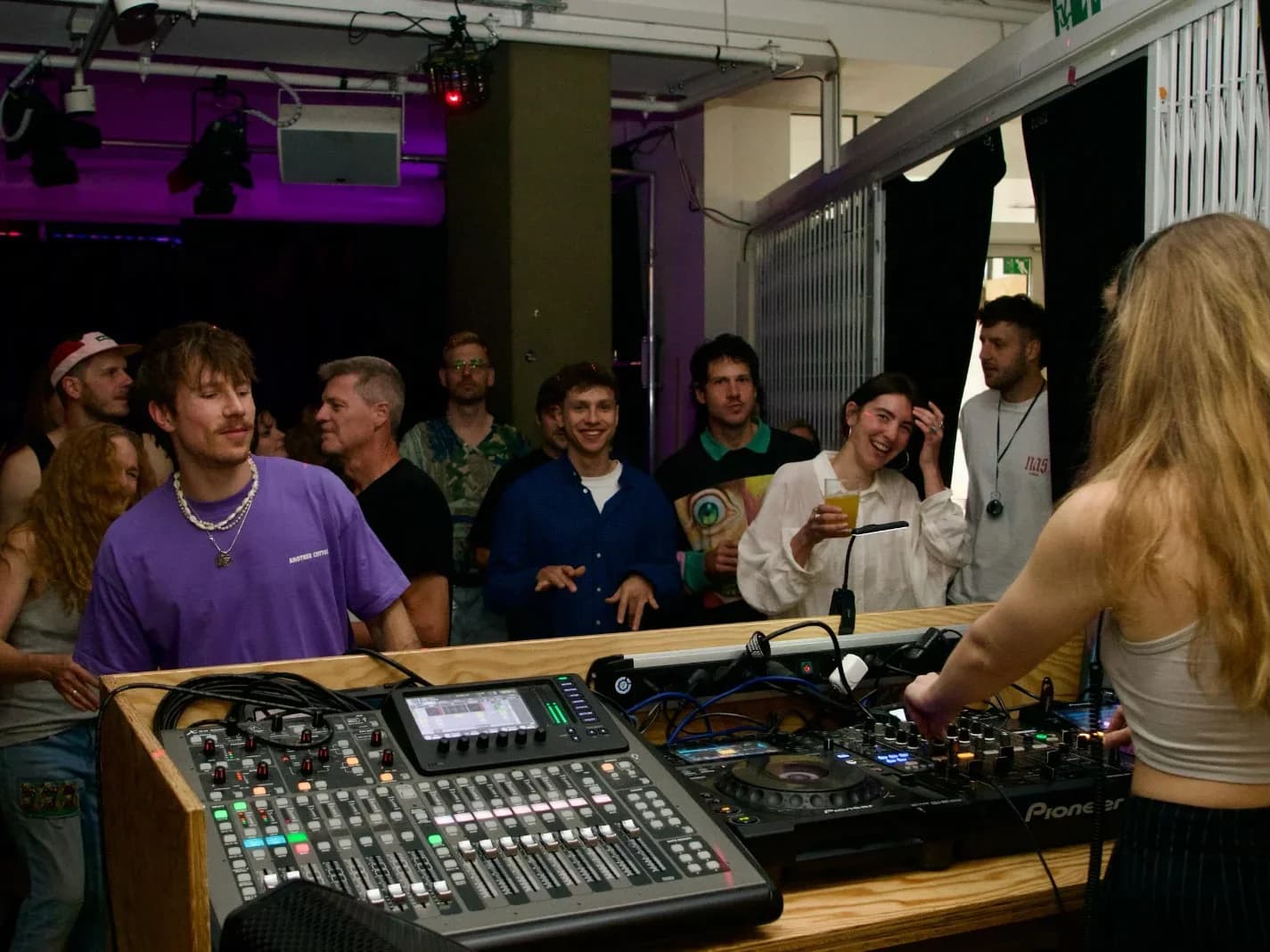 Eine DJ legt am Mischpult auf, vor ihr tanzen und lachen die Gäste im Degginger Club.