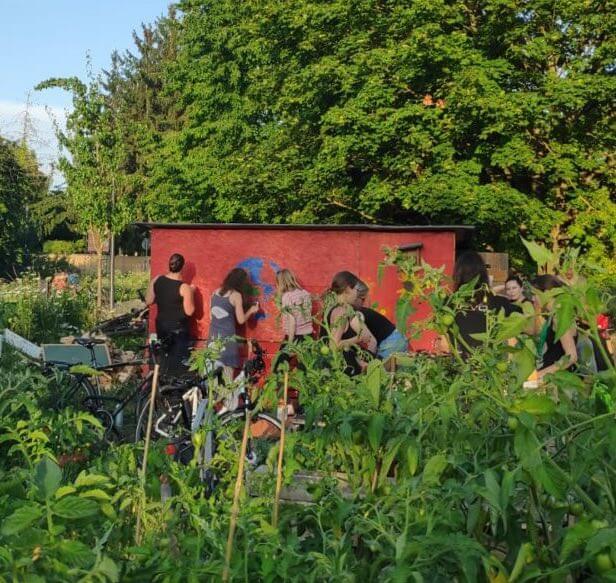 Der interkulturelle Garten von Campus Asyl mit Mitgliedern vor dem Bauwagen.