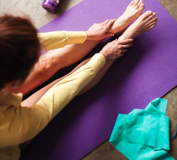 Eine Frau beim Pilates im REKiZ, welche eine Pilates-Übung auf einer lila Yoga-Matte macht.