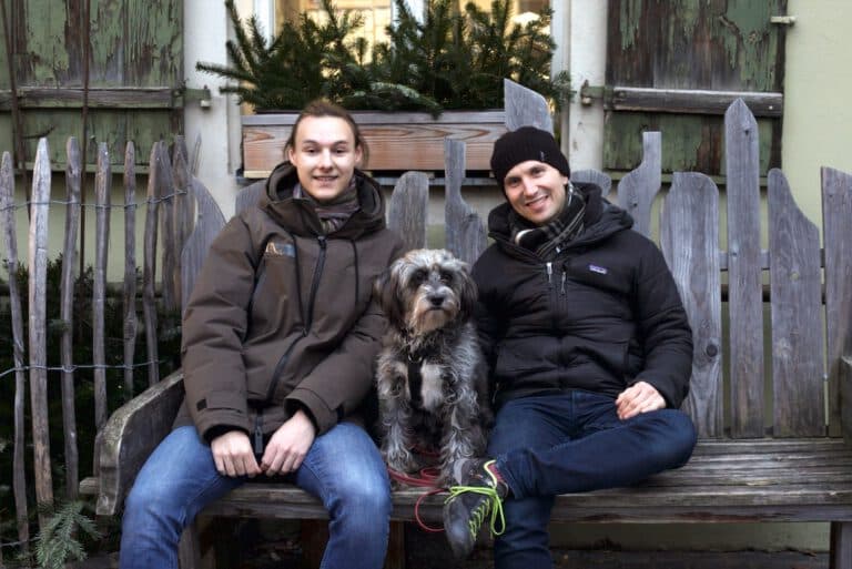 Danylo Tkach und Fabian Kreipl von rudel auf einer Bank, gemeinsam mit Bürohund "Lou".