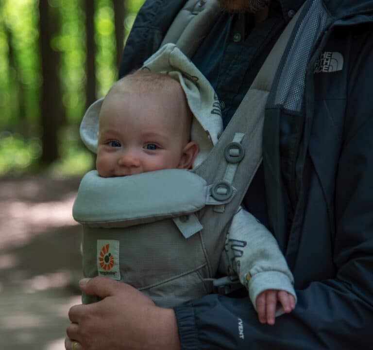 Ein Baby, welches von seinem Vater getragen wird. Nahaufnahme in der Natur stellvertretend für die Trageberatung von Herztöne.