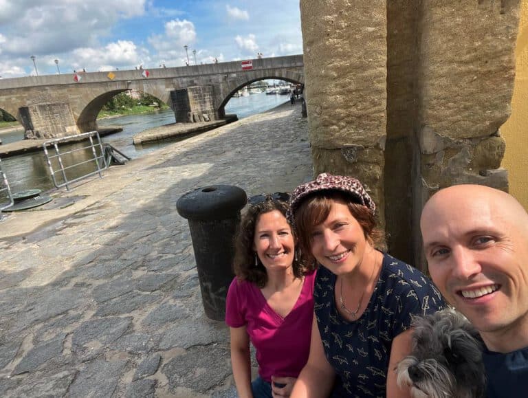 Das Rudel-Team mit Anna von Ammon, Sarah Walther-Young, sowie Fabian Kreipl und Hund Lou hinter der steinernen Brücke in Regensburg.