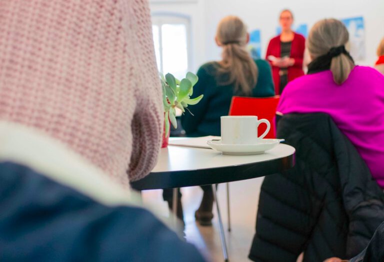 Senioren sitzen bei einem Vortrag mit Kaffee in der Regensburger Stadtbücherei.