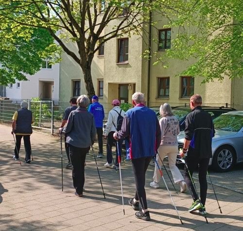 Eine Gruppe Senioren geht mit Walking Stöcken im Park mit der Nordic Walking Gruppe spazieren.