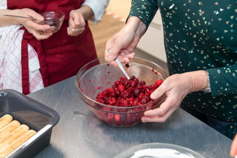 Senioren bereiten eine Nachspeise mit frischen Beeren zu.