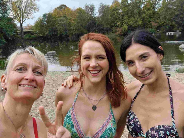 Drei Frauen gehen im Winter am See eisbaden.