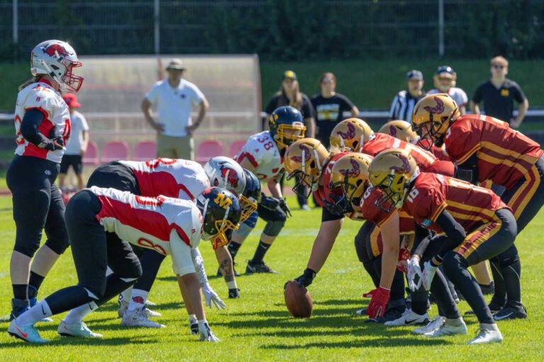 Zwei Frauenteams des American Football stehen sich auf dem Spielfeld gegenüber.