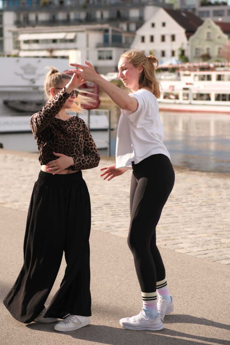 Tanzlehrerin Tine tanzt mit einer Frau. Im Hintergrund ist die Donau.